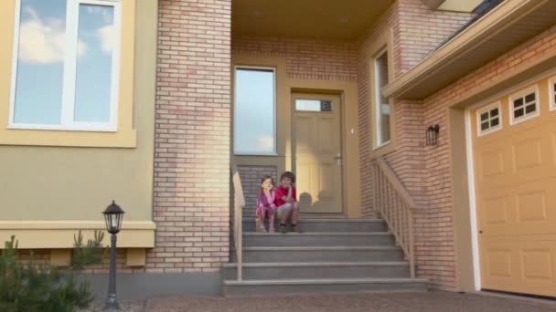 Twee kinderen zitten op de veranda — Stockvideo