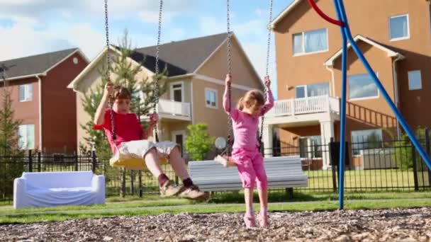 Мальчик и девочка качаются на качелях — стоковое видео