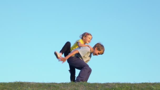 Kleines Mädchen klettert Bruder auf den Rücken — Stockvideo