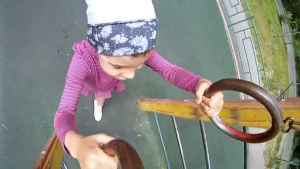 Mała dziewczynka zawiesza się na sportowe pierścienie — Wideo stockowe