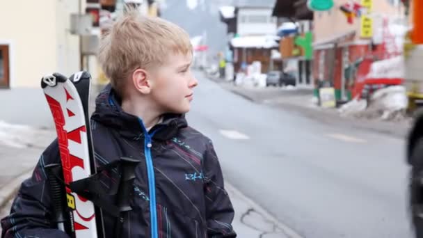 Niño con esquís se para en la calle — Vídeo de stock