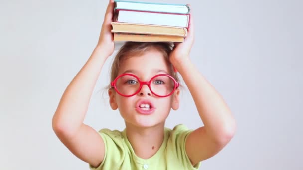 Kleines Mädchen mit Büchern auf dem Kopf — Stockvideo