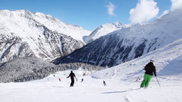 Лыжники идут по горному склону — стоковое видео