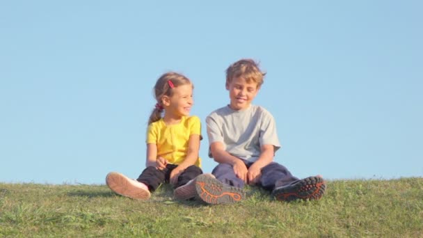 Two kids talk on grass hill — Stock Video