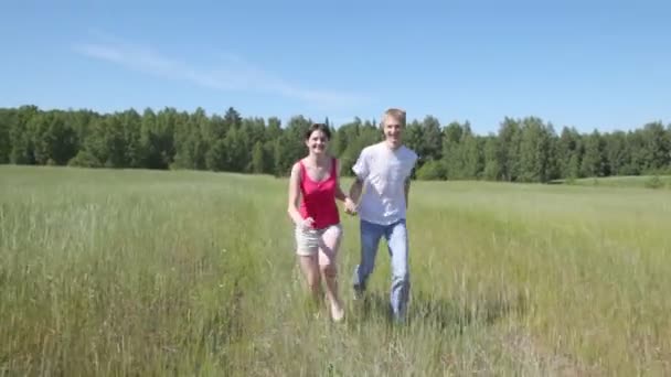 Парень с девушкой бегает по полю — стоковое видео