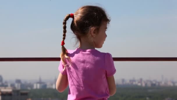 Маленькая девочка противостоит городскому пейзажу — стоковое видео