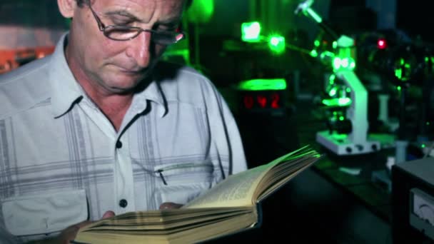 Man reads book in dark lab — Stock Video