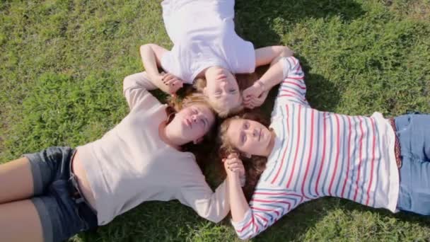 Три дівчини лежали на траві — стокове відео