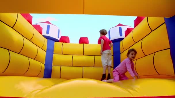 Boy and girl at inflatable playground — Stock Video