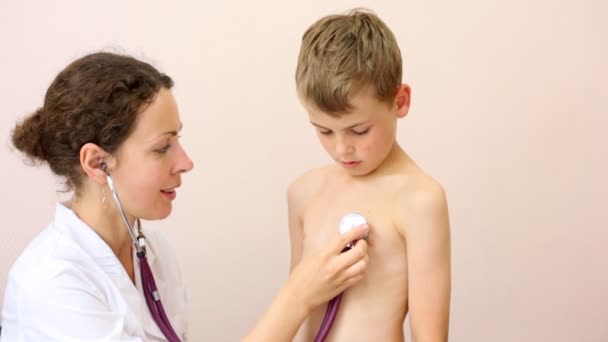 Woman doctor listens to breast of boy