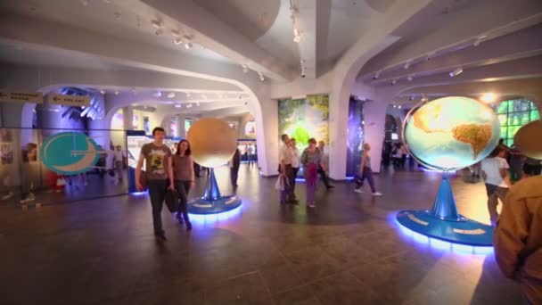 Туристы ходят среди моделей планет — стоковое видео