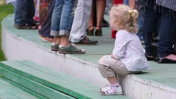Niezidentyfikowane dziecko siedzi na kroki na koncercie — Wideo stockowe