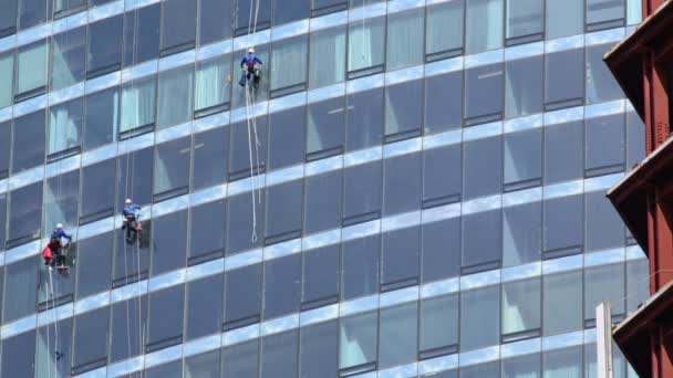 Tři zaměstnanci umýt okna mrakodrapu