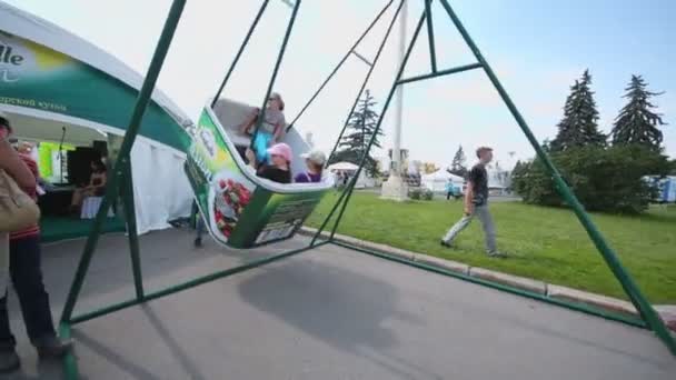 Folk går nära Bonduelle paviljong med swing — Stockvideo