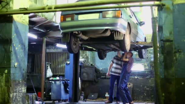 Doi bărbați examinează fundul mașinii — Videoclip de stoc