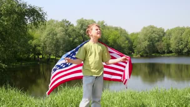 Мальчик держит развернутый флаг США — стоковое видео