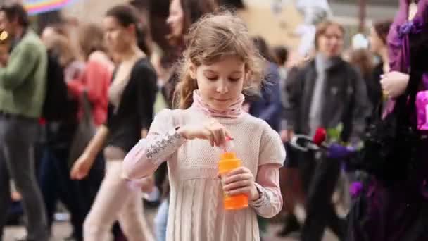 Маленькая девочка надувает мыльные пузыри — стоковое видео