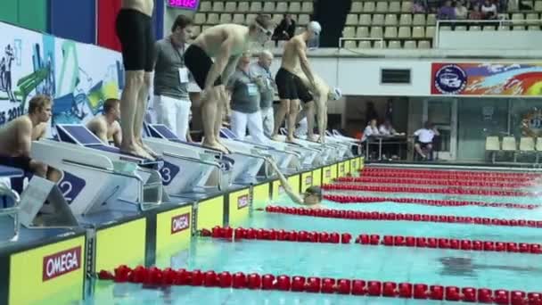 Swimmers jump into water in swimming pool — Stock Video