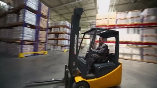 Man rides on loader in warehouse — Stock Video