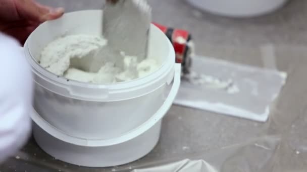 Worker in white uniform mixes putty — Stock Video