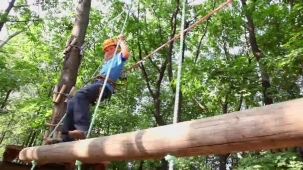 Niño en casco camina en el parque de cuerdas — Vídeos de Stock