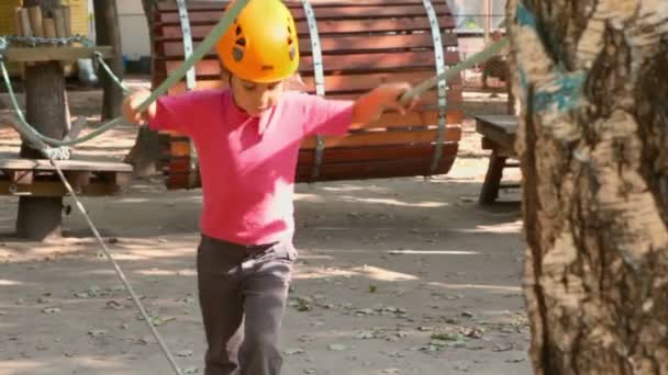 Маленькая девочка ходит по веревке на детской площадке — стоковое видео