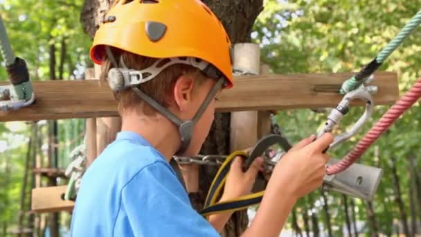 Young boy in helmet connects hook — Stock Video