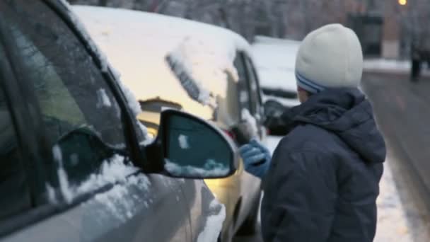 Młody chłopak czyści samochodu ze śniegu — Wideo stockowe