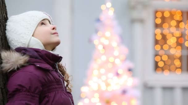Очаровательная маленькая девочка стоит рядом с деревом — стоковое видео