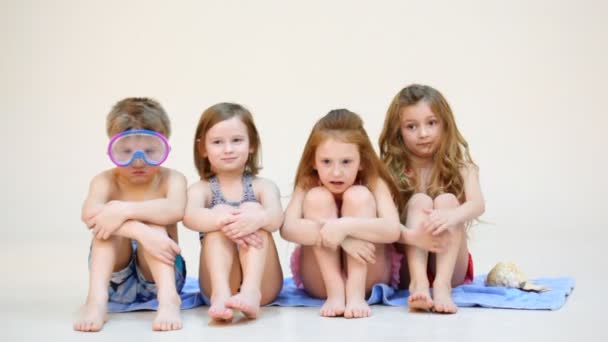 Cuatro niños se sientan en la toalla de playa — Vídeos de Stock