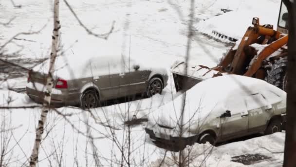 Bulldozer removes snow between cars — Stock Video