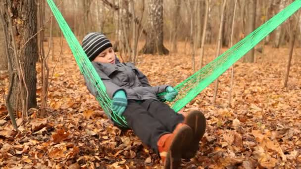 Lindo chico balanceándose en hamaca verde — Vídeos de Stock