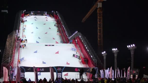 Люди смотрят, как спускаются сноубордисты — стоковое видео