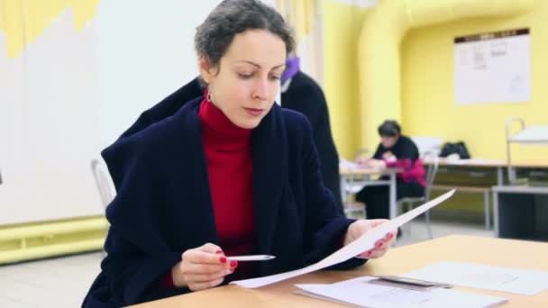 Une femme choisit un candidat parmi les bulletins de vote — Video