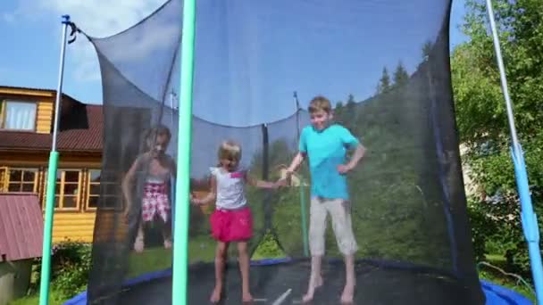 Boy with little girls jump on trampoline — Stock Video