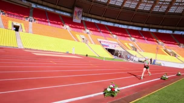 Desportista corre por pista durante a corrida — Vídeo de Stock