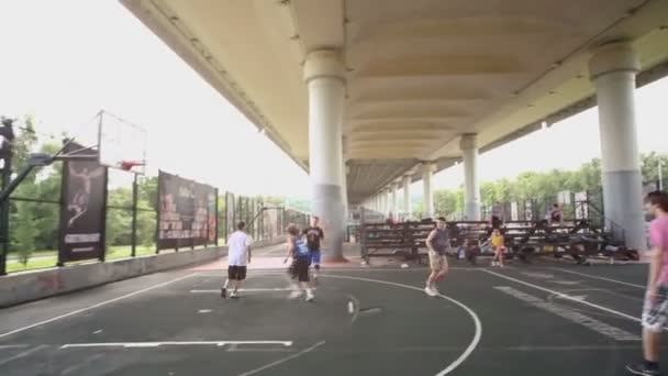 Mensen spelen basketbal op speelplaats — Stockvideo