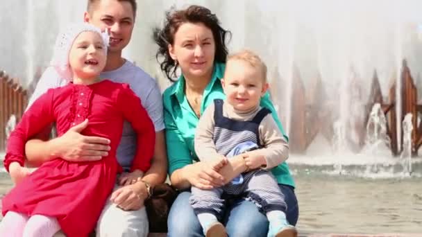 Fyra personer familjen sitta nära fountain — Stockvideo