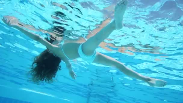 Маленькая девочка, плавающая в голубом бассейне — стоковое видео