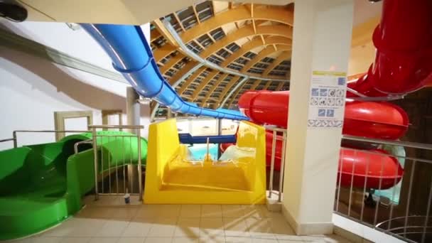 Toboganes acuáticos interiores multicolores en aquapark — Vídeos de Stock