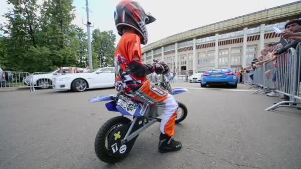 Niño en traje de motociclista en bicicleta pequeña — Vídeo de stock