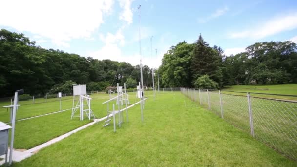 Modern meteostation on green field with fence — Stock Video