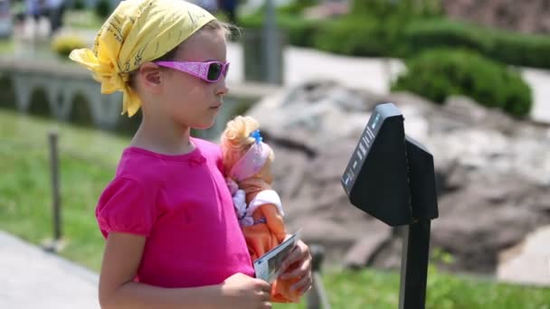 Girl with doll listening electronic guide — Stock Video