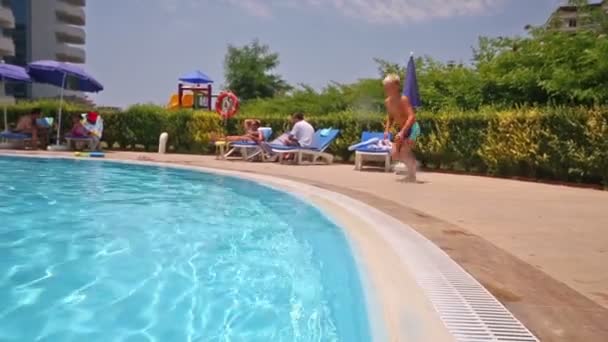 Menino salta na piscina — Vídeo de Stock