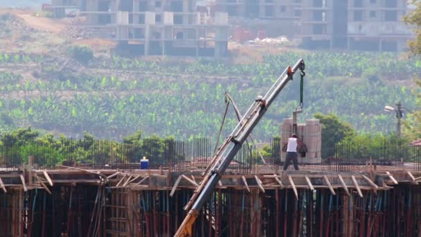 La grúa ayuda a los constructores a levantar materiales — Vídeo de stock