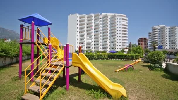 Parque infantil con tobogán en espiral y columpios en hotel — Vídeos de Stock