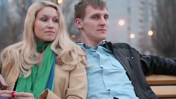 Молодая пара сидит на скамейке — стоковое видео