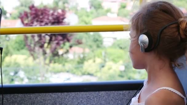 Meisje in hoofdtelefoon rijden met sightseeing bus — Stockvideo