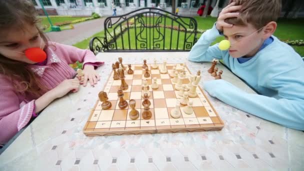 Junge und Mädchen spielen Schach im Park — Stockvideo