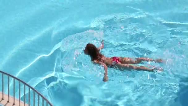 Młoda kobieta w czerwony strój kąpielowy pływa — Wideo stockowe